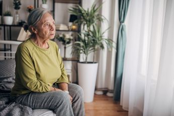 Einsame alte Frau sitzt im Wohnzimmer
