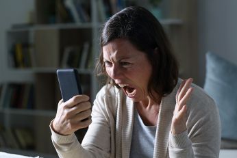 Frau mit wütendem Gesicht schaut auf das Mobiltelefon