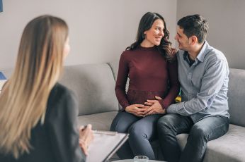 Paar nimmt an einer Beratung teil. Die Frau ist schwanger. 