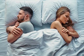 Couple in bed, lying separately showing their backs