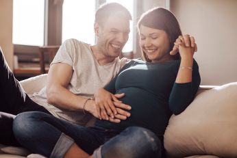 Young couple expecting a child sitting on the couch