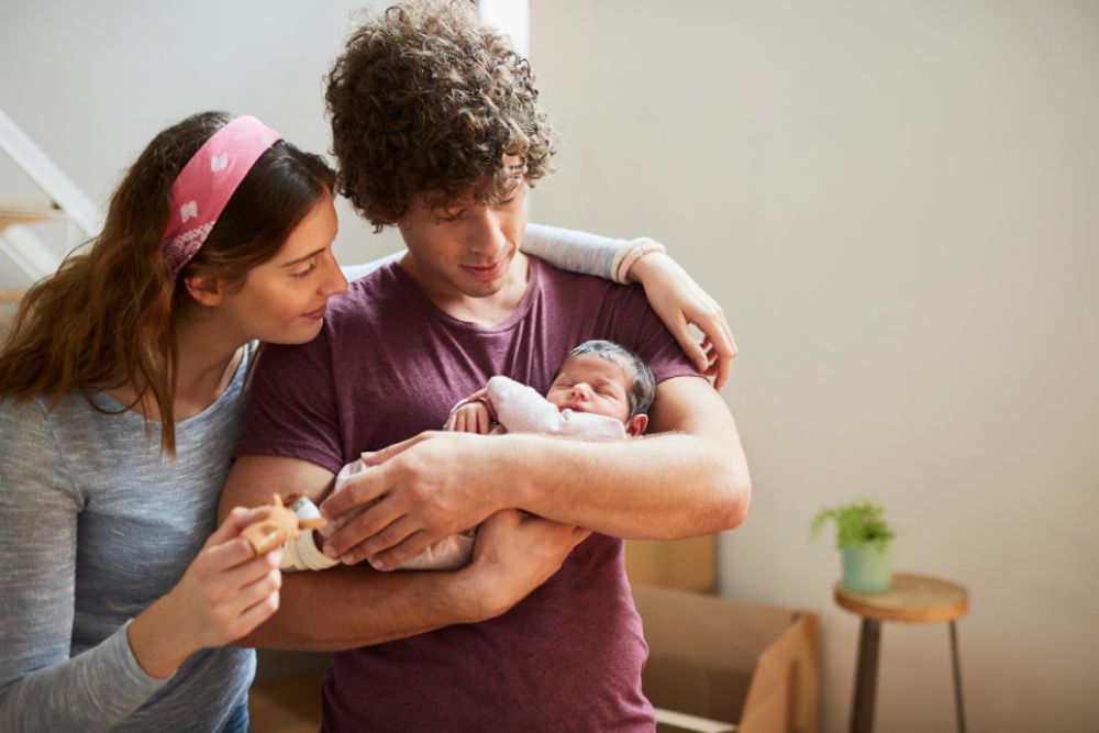 A young couple is looking at its newborn.