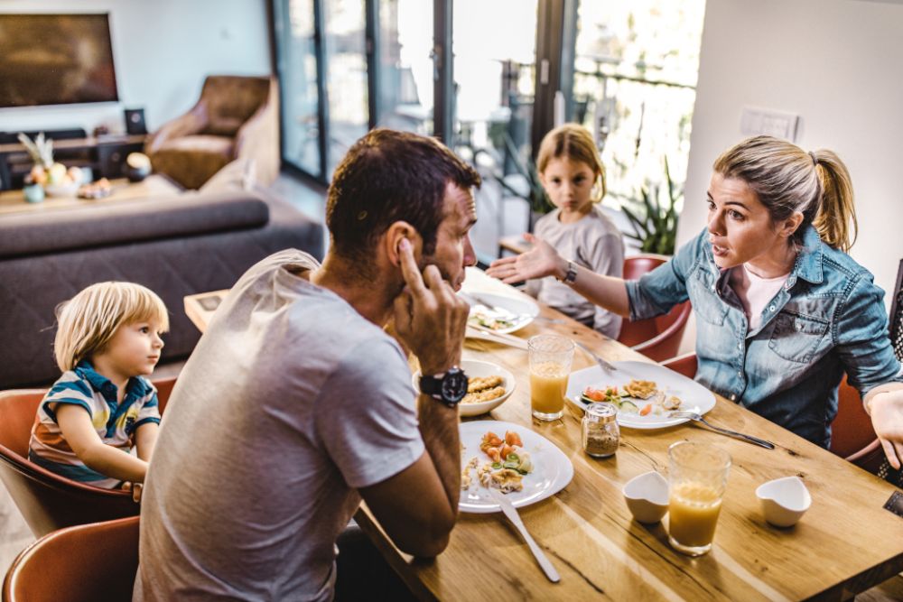 A couple is arguing beside their children.