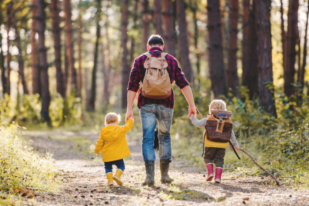 Ein Vater geht mit seinen zwei kleinen Kindern wandern.