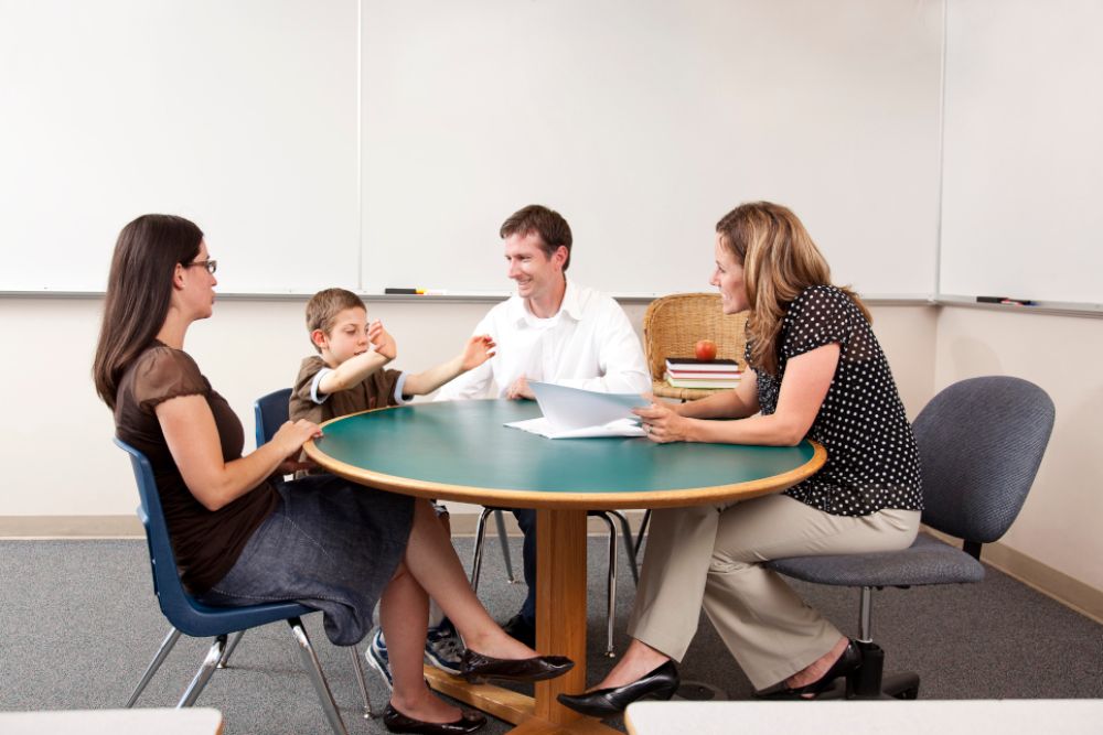 Eine Familie sitzt mit einer Beraterin an einem runden Tisch.