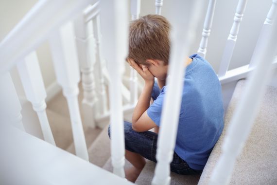 Junge sitzt weinend auf einer Treppe.