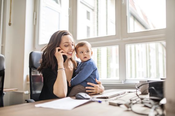 Mutter telefoniert mit Kind am Bürotisch