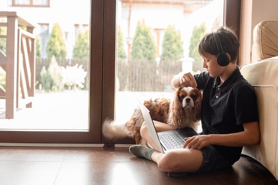 Kind mit Hund und Kopfhörern in Zimmer.