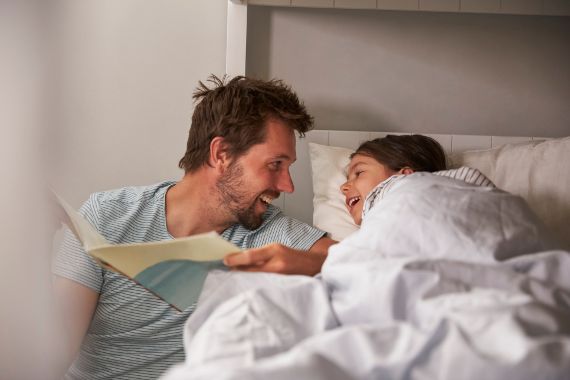 A father is reading a good night story to his child. 