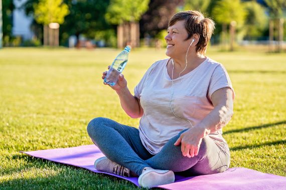 Women is sitting on the ground after physical exercise. She is smiling.