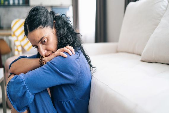 Women sitting floor. She looks sad. 