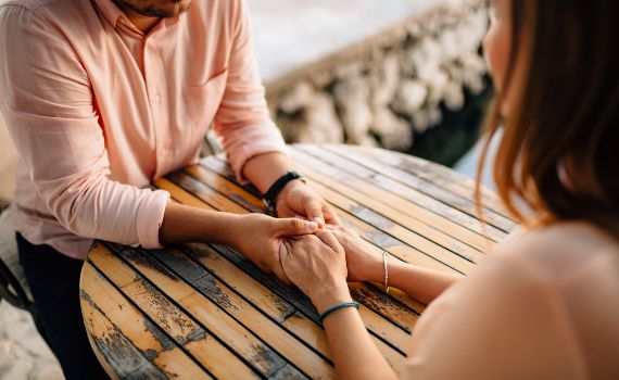 Couple sitting eye to eye and holding each others hands.