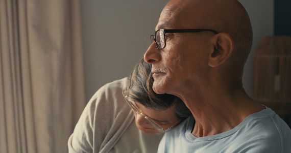 Elderly couple cuddling – they seem to be sad.