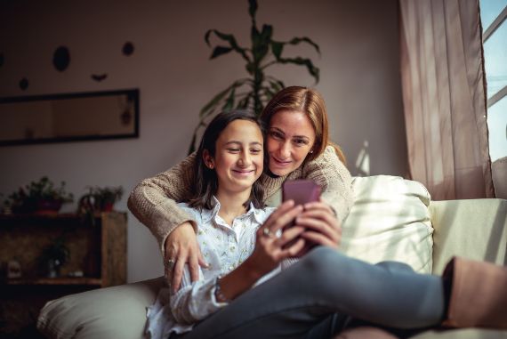 Mother and teenage-daughter sitting on the couch.