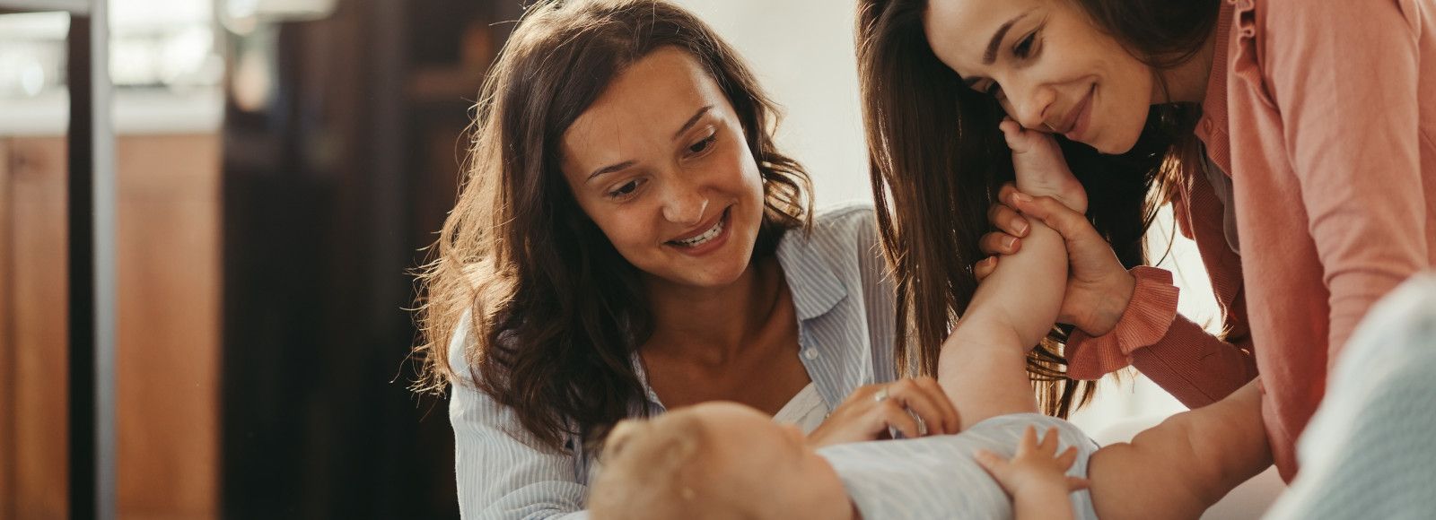 Two women play with a baby.