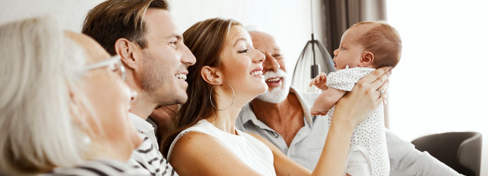 A young family shows their baby to the grandparents.